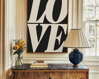 Puede incluir: Una impresión enmarcada en blanco y negro de la palabra "LOVE" en letras negritas y en bloque. La impresión está colgada en una pared sobre una cómoda de madera oscura con una tapa de mármol negro. Una lámpara con una pantalla blanca se encuentra sobre la cómoda.