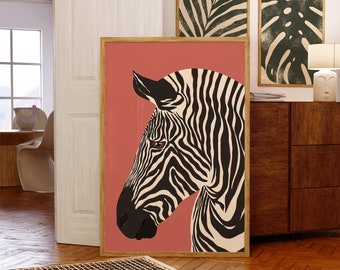 Puede incluir: Una impresión artística enmarcada que presenta una cabeza de cebra estilizada con rayas blancas y negras sobre un fondo coral. Se ven impresiones botánicas enmarcadas adicionales, creando un efecto de pared de galería. La obra de arte se exhibe en una habitación con muebles de madera.