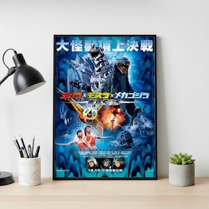 May include: Framed movie poster featuring Godzilla, Mothra, and Mechagodzilla. The poster has a blue background with Japanese text at the top and the movie title in Japanese characters. The poster also includes images of people and dates.