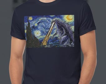 May include: Navy blue t-shirt featuring a graphic of Godzilla in a reinterpretation of Van Gogh's "Starry Night." The design includes swirling blue and yellow brushstrokes, a yellow moon, and a cityscape silhouette.