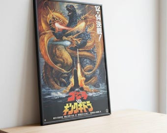 Op de afbeelding: Ingelijste poster met een gevechtsscène met Godzilla en een driekoppige draak. Het kunstwerk gebruikt goud-, oranje- en blauwtinten. Japanse tekst staat onderaan, met de datum "12.14" aan de rechterkant.