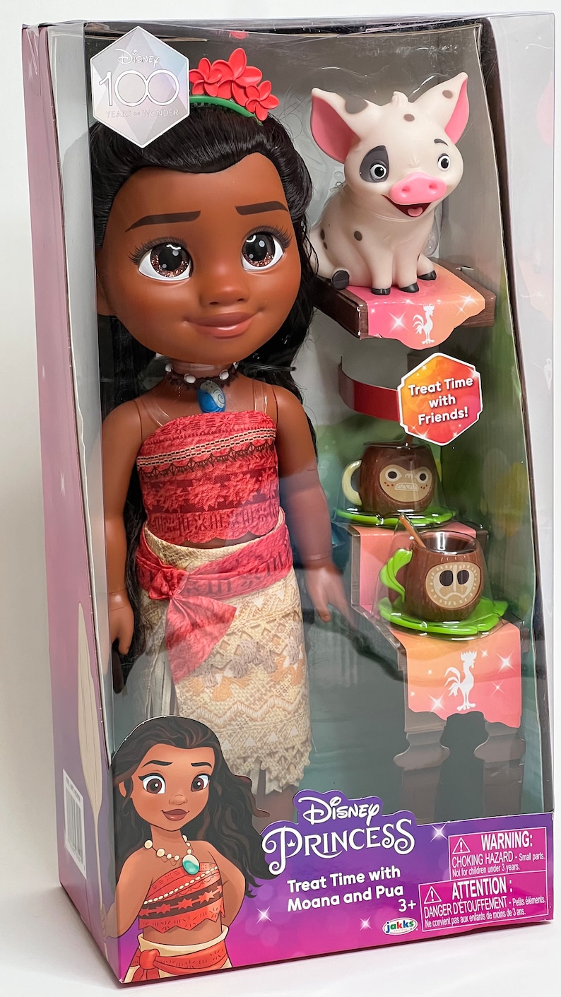 May include: A Disney Princess Moana doll set in a clear plastic package. The doll has dark hair, a red top, and a patterned skirt. The set includes a Pua pig figure and two coconut-shaped mugs. The packaging includes the text "Treat Time with Moana and Pua."