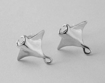 Könnte beinhalten: Ein Paar silberne Ohrringe in Form von Mantarochen. Die Ohrringe sind schlicht gehalten und haben eine glatte, polierte Oberfläche.