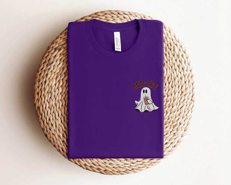 May include: Purple t-shirt with a white ghost holding a brown beverage and the text "BOO-JEE" in black.