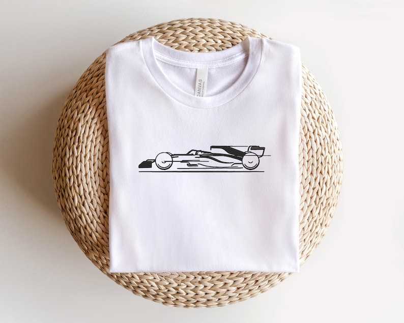 May include: White t-shirt with a black silhouette of a racing car on the front.