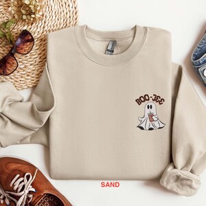 May include: A sand-colored sweatshirt with a ghost holding a cup of coffee and the text "BOO-JEE" printed on the front.
