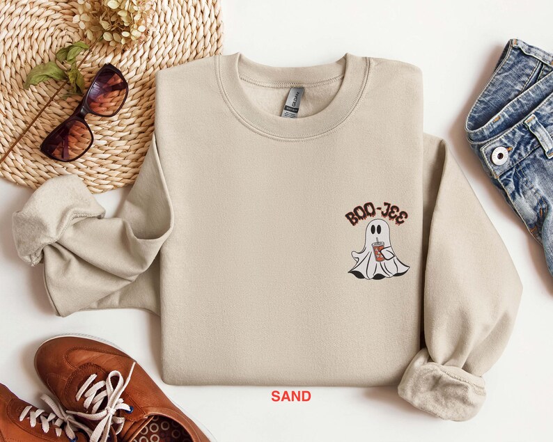 May include: A sand-colored sweatshirt with a ghost holding a cup of coffee and the text "BOO-JEE" printed on the front.