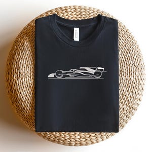 May include: Black t-shirt with a white outline of a racing car.