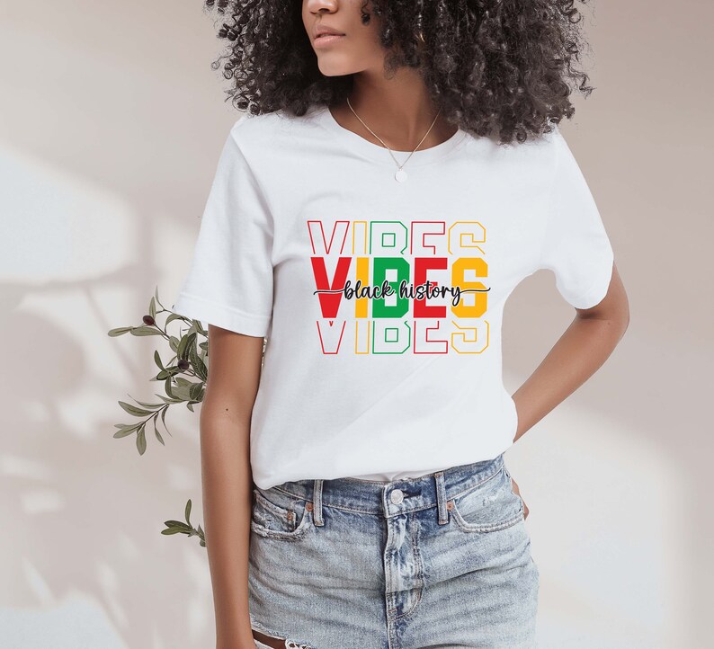 May include: White t-shirt with the words "VIBES" stacked on top of each other in red, yellow, and green. The words "black history" are written in black cursive script between the two sets of "VIBES".