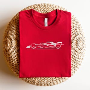May include: Red t-shirt with a white outline of a racing car.