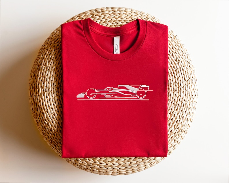 May include: Red t-shirt with a white outline of a racing car.