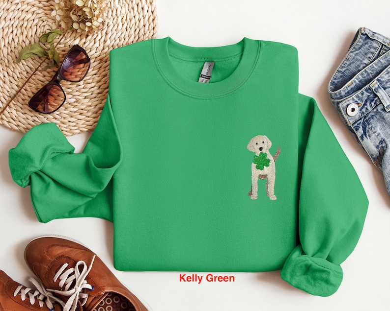 May include: A kelly green sweatshirt with a white crew neck and a small embroidered image of a golden retriever holding a shamrock.
