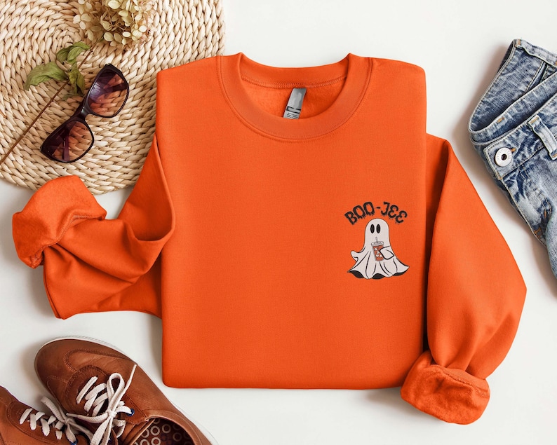 May include: Orange sweatshirt with a ghost holding a cup and the text "BOO-JEE" printed on the front.