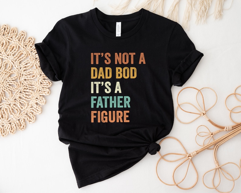 Pu&ograve; includere: Maglietta nera con una grafica in stile vintage che recita "Non &egrave; un fisico da pap&agrave;, &egrave; una figura paterna."