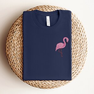 May include: A navy blue t-shirt with a pink flamingo embroidered on the front.