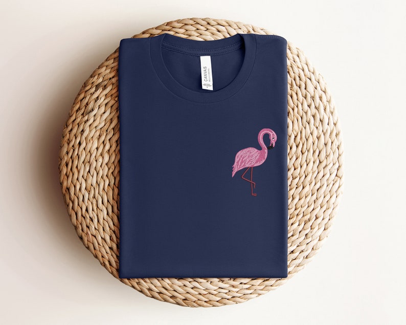 May include: A navy blue t-shirt with a pink flamingo embroidered on the front.