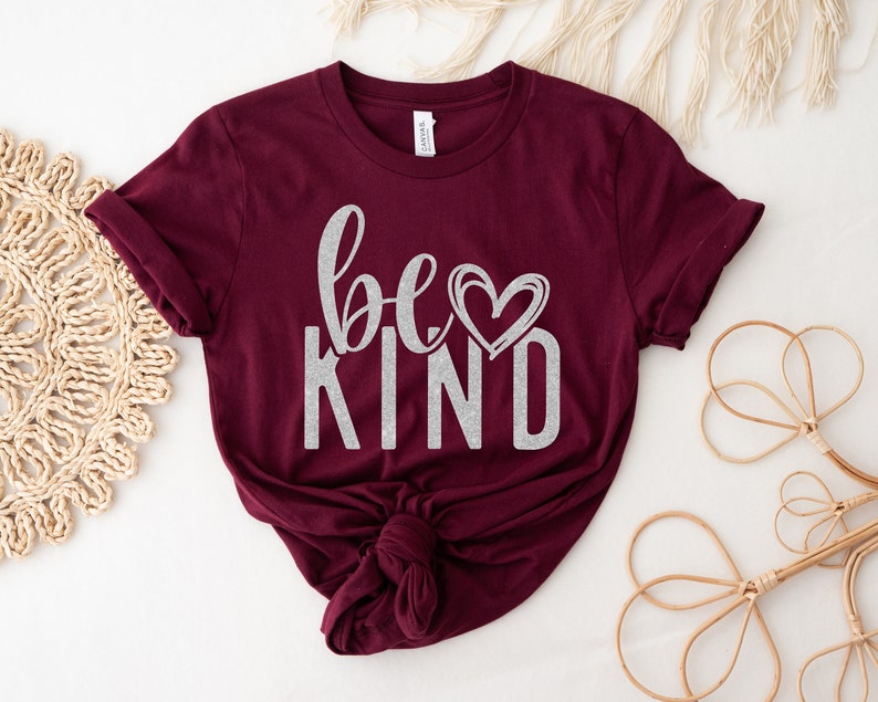 May include: Burgundy t-shirt with a silver glitter design that says "be kind" with a heart.