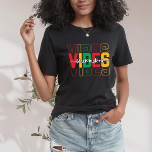 May include: Black t-shirt with the text "VIBES" in red, yellow, green, and black letters. The text "black history" is written in white script across the middle of the shirt.