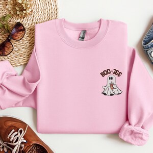 May include: Pink sweatshirt with a ghost holding a cup of coffee and the text "BOO-JEE" on the front.