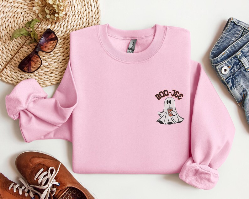 May include: Pink sweatshirt with a ghost holding a cup of coffee and the text "BOO-JEE" on the front.
