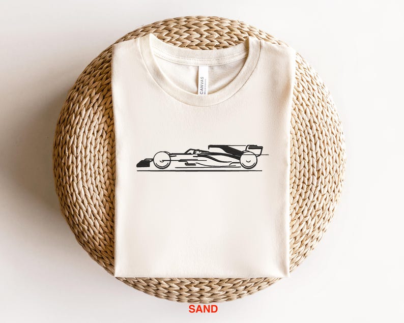 May include: A white t-shirt with a black silhouette of a racing car printed on the front. The car is facing to the right and has a black and white design.
