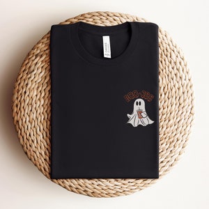 May include: Black t-shirt with a white ghost holding a brown beverage cup and the text "Boo-Jee" in orange.