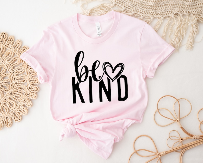 May include: Pink t-shirt with black text that reads "be kind" with a heart graphic.