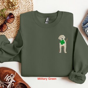 May include: A military green sweatshirt with a white embroidered shamrock and a yellow labrador retriever wearing a green shamrock around its neck.