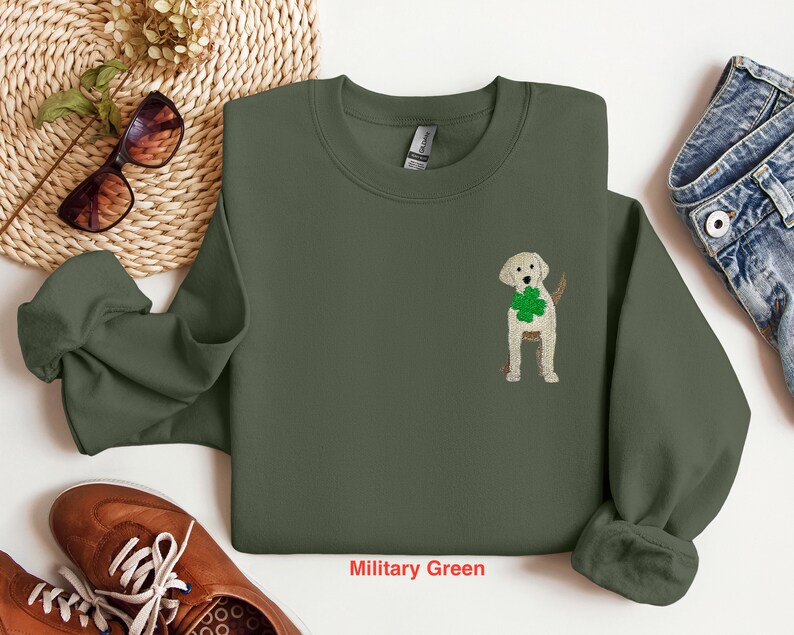 May include: A military green sweatshirt with a white embroidered shamrock and a yellow labrador retriever wearing a green shamrock around its neck.