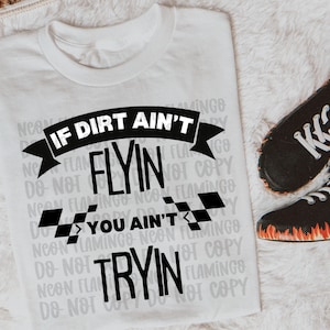 May include: White t-shirt with black text that reads "If dirt ain't flyin' you ain't tryin'" with a checkered flag design. The text is in a bold, handwritten font.
