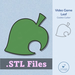 May include: A green leaf-shaped cookie cutter with a black outline, next to a smaller outline of the same shape. The text "Video Game Leaf Cookie Cutter" is displayed. The words ".STL Files" are also visible.
