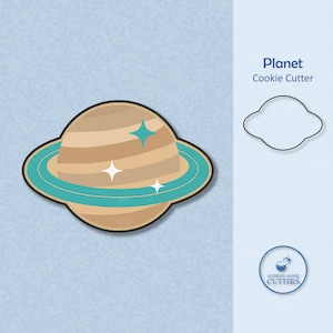 May include: A cookie cutter shaped like a planet with rings and stars. The cookie cutter is made of metal and is a light brown color. The planet has a teal ring around it. The cookie cutter is on a light blue background. The text "Planet Cookie Cutter" is in the top right corner of the image.
