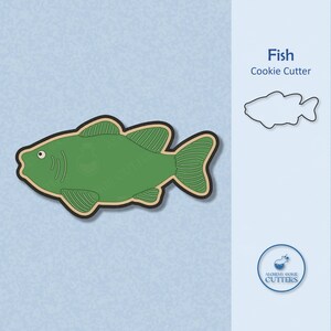 May include: A green fish-shaped cookie cutter with a black outline and tan border. The image also includes a line drawing of the fish shape and the text "Fish Cookie Cutter". The Alchemy Cookie Cutters logo is in the bottom right corner.