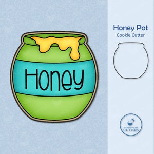 May include: A green and yellow honey pot cookie cutter with the word "Honey" on the front. The cutter is designed to create a cookie that looks like a honey pot.