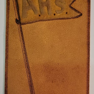 May include: A brown leather patch with a yellow felt flag that says "AHS" and the text "ANAHEIM, CAL." in black ink.