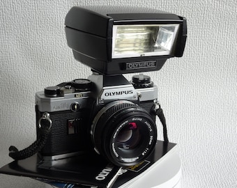 Olympus OM-10 + Olympus Lens 50mm 1:1.8 OM Zuiko System + Olympus T32 Auto Flash + lens cap + Olympus instruction