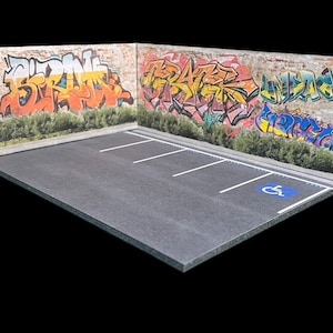 May include: A miniature model of a parking lot with two brick walls covered in colorful graffiti. The walls are painted with the words "STRIVE" and "SPACE". The parking lot has three parking spaces with white lines and a blue handicapped symbol.