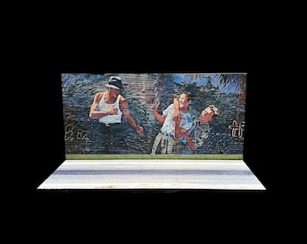 May include: A mural depicting three people in a tropical setting. The people are wearing casual clothing and are interacting with each other. The mural is painted on a brick wall and has a faded, vintage look.