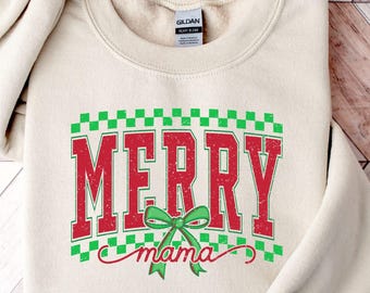 Puede incluir: Sudadera de color arena con las palabras "MERRY mama" en rojo, contorneadas en verde, y un lazo verde. La palabra "MERRY" está en negrita, con un estilo universitario, y "mama" está en cursiva. La sudadera está doblada.