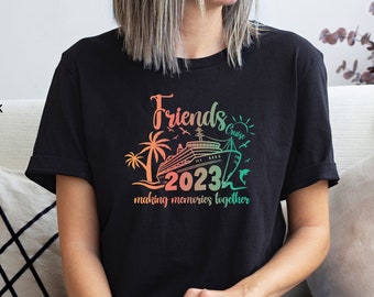 Op de afbeelding: Zwart T-shirt met een kleurrijke afbeelding van een cruiseschip en palmbomen. De tekst "Friends Cruise 2023 making memories together" staat op het shirt gedrukt.