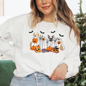 May include: White sweatshirt with a graphic of four dogs dressed as ghosts for Halloween. The dogs are holding pumpkins and there are bats and spiderwebs in the background.