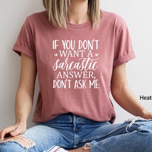 May include: A heather mauve t-shirt with the text "If you don't want a sarcastic answer, don't ask me" printed in white. The shirt is being modeled by a person wearing blue jeans.