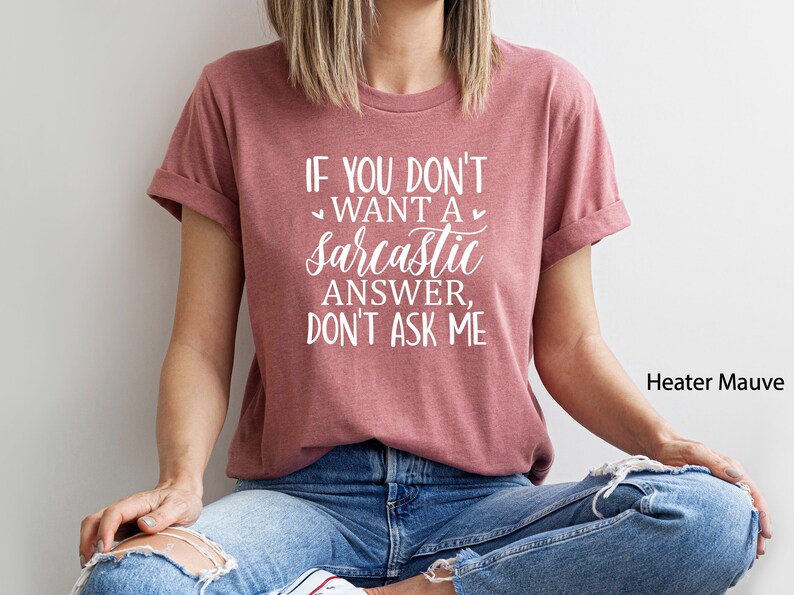 May include: A heather mauve t-shirt with the text "If you don't want a sarcastic answer, don't ask me" printed in white. The shirt is being modeled by a person wearing blue jeans.