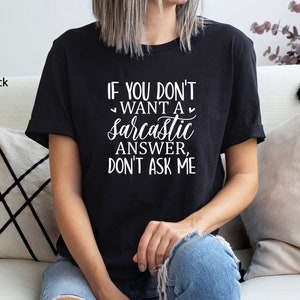 May include: A black t-shirt with white text that reads "If you don't want a sarcastic answer, don't ask me."