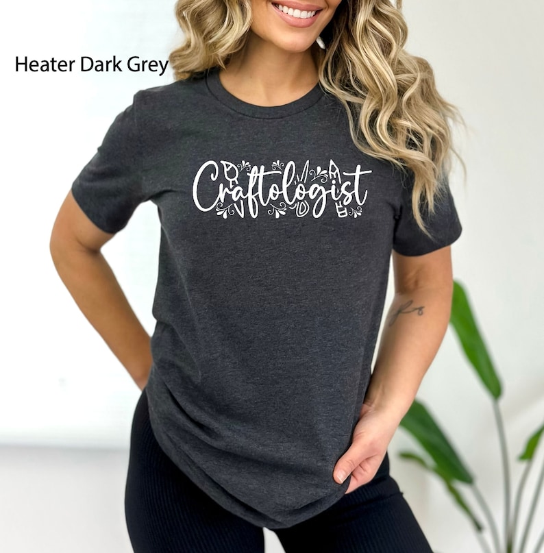 May include: A dark grey t-shirt with the text "Craftologist" in white lettering. The text is surrounded by small decorative elements.