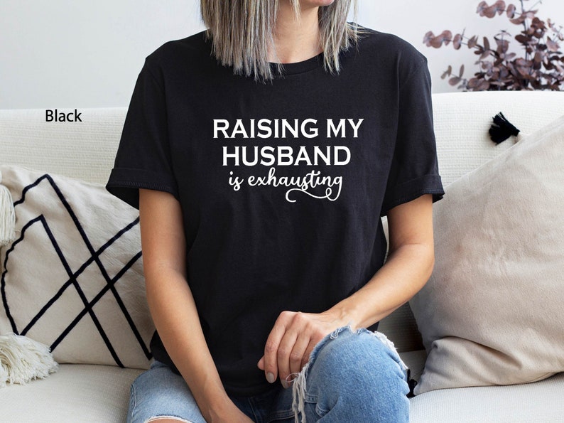May include: Black t-shirt with the text "Raising my husband is exhausting" in white lettering.