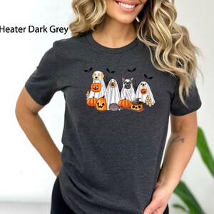 May include: A dark grey t-shirt with a graphic of five dogs dressed as ghosts for Halloween. The dogs are holding pumpkins and candy. The text "Heater Dark Grey" is visible in the top left corner of the image.