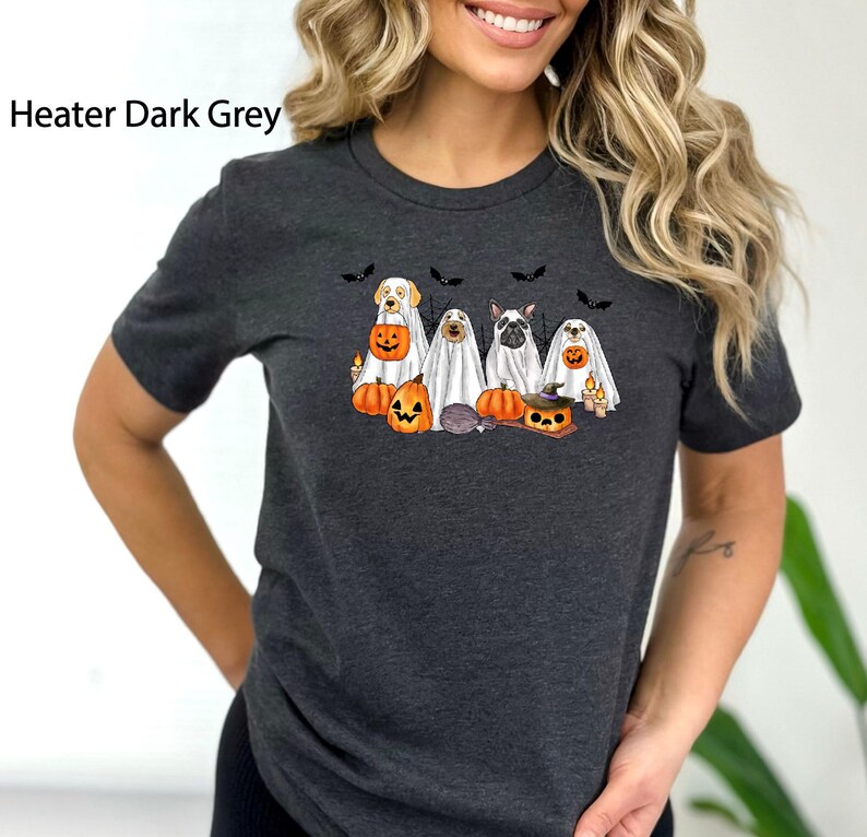 May include: A dark grey t-shirt with a graphic of five dogs dressed as ghosts for Halloween. The dogs are holding pumpkins and candy. The text "Heater Dark Grey" is visible in the top left corner of the image.