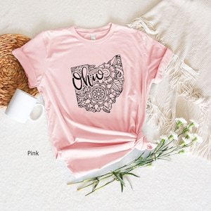 May include: Pink t-shirt with a black outline of the state of Ohio with a mandala design and the word "Ohio" inside the state outline.