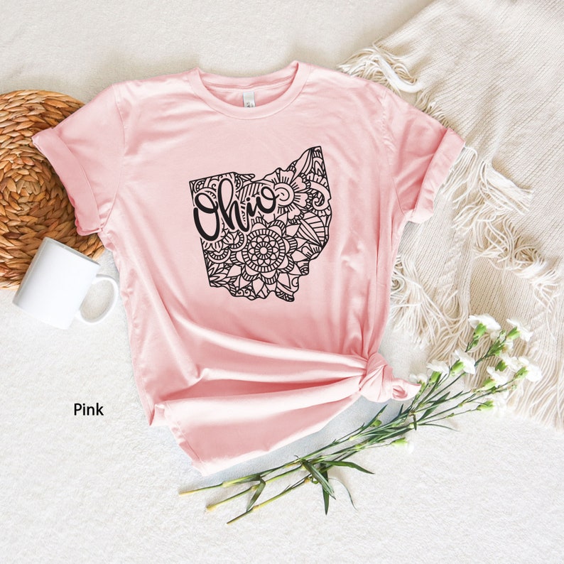 May include: Pink t-shirt with a black outline of the state of Ohio with a mandala design and the word "Ohio" inside the state outline.